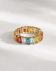 Gold ring with multicolored gemstones on a light gray background