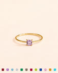 Gold ring with a purple gemstone on a beige background