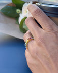 Hand wearing a colorful ring with a blurred background