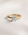 Gold ring with a 1ct round diamond on a light gray background