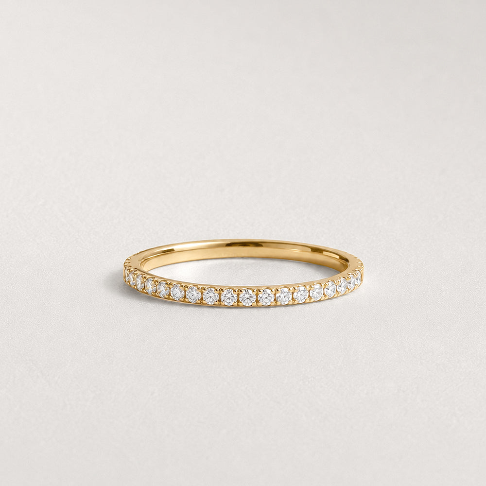 Gold ring with small diamonds on a light gray background