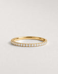 Gold ring with small diamonds on a light gray background