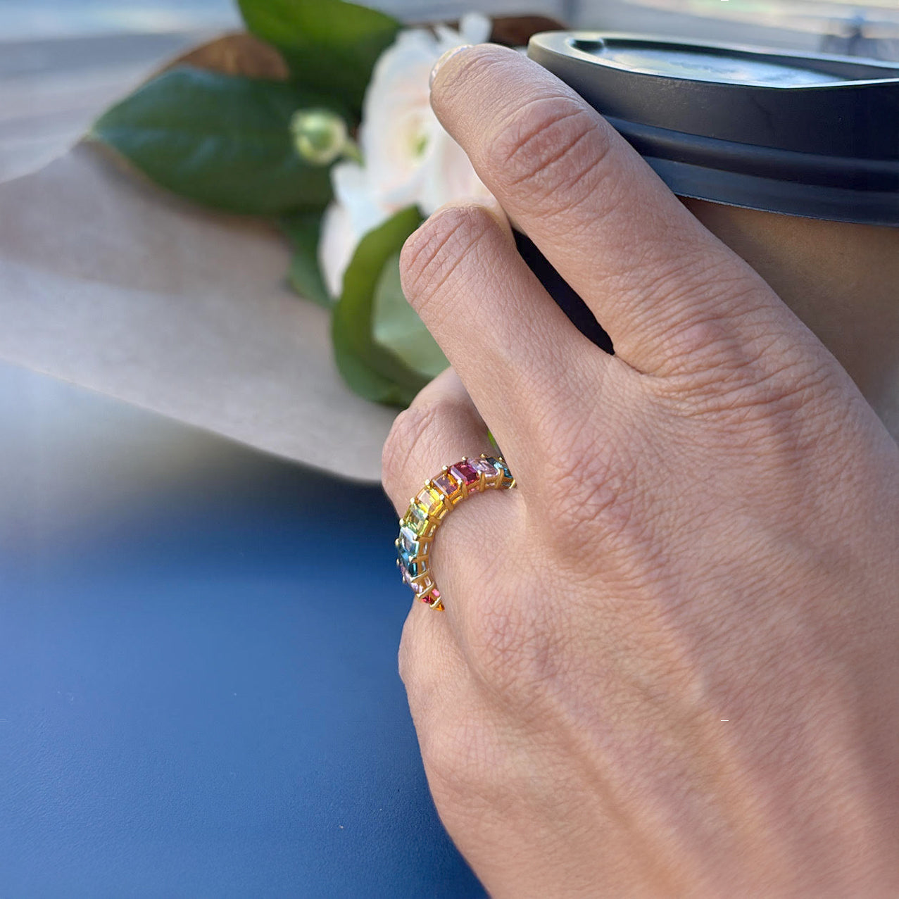 Hand wearing a colorful ring with a blurred background